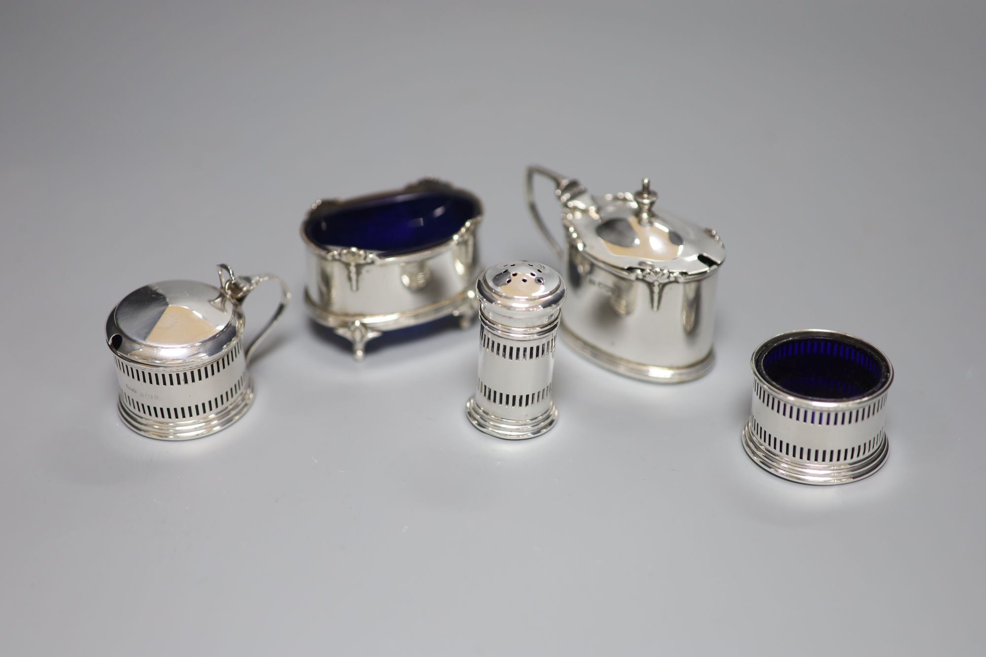 A George V small silver three piece condiment set, Birmingham, 1932 and two other silver condiments.
